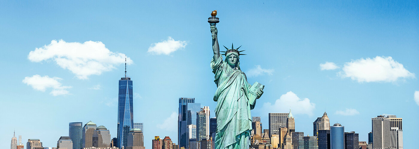 Im Vordergrund die Freiheitsstatue in New York, dahinter Manhatten