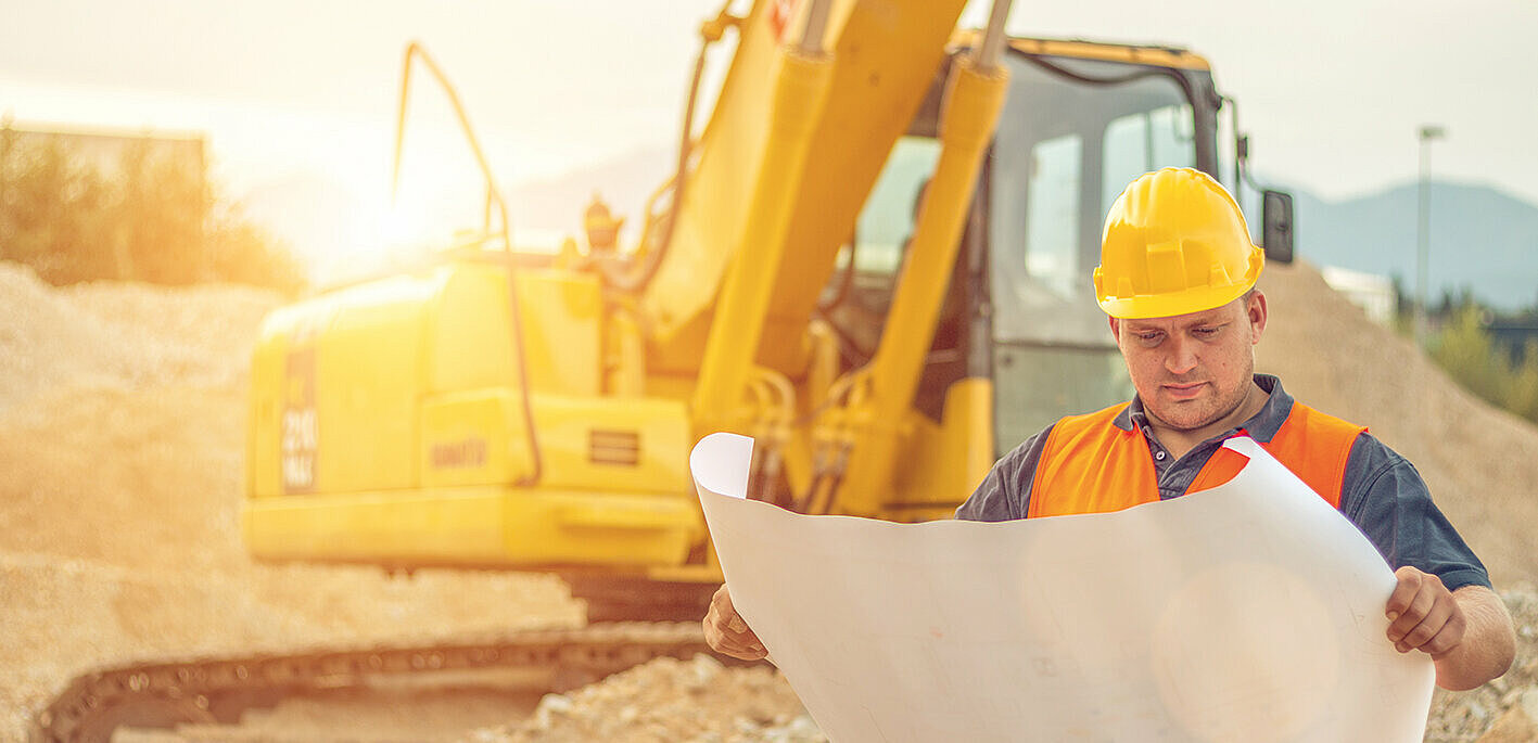 Bauleiter mit Bagger im Hintergrund