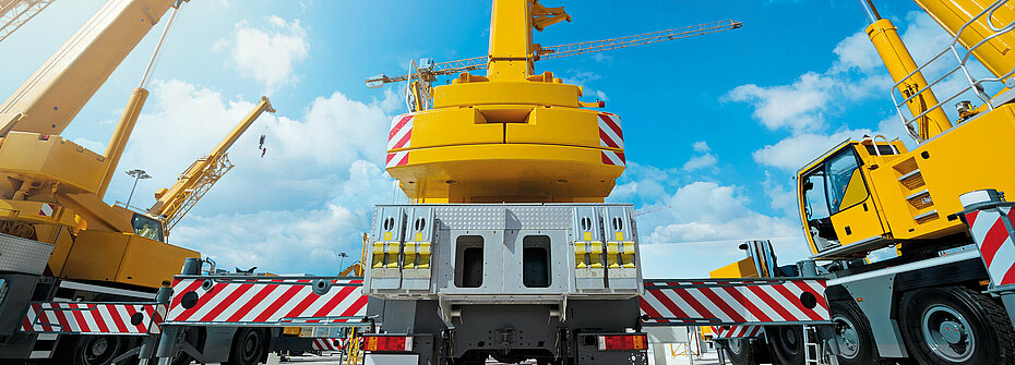 Rear view of three yellow mobile cranes